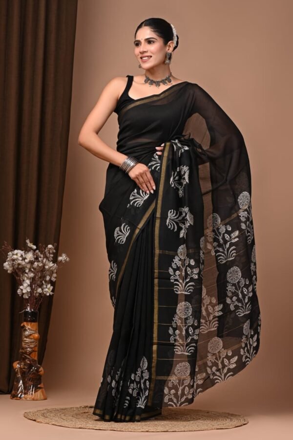 Woman draped in black Chanderi silk saree with white floral hand block print border and golden trim