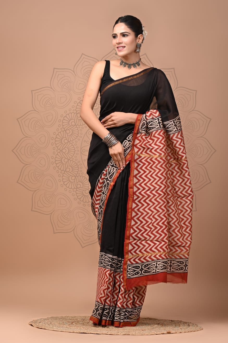 Woman in black Chanderi silk saree with rust-red zigzag chevron pallu, Bagru hand block print