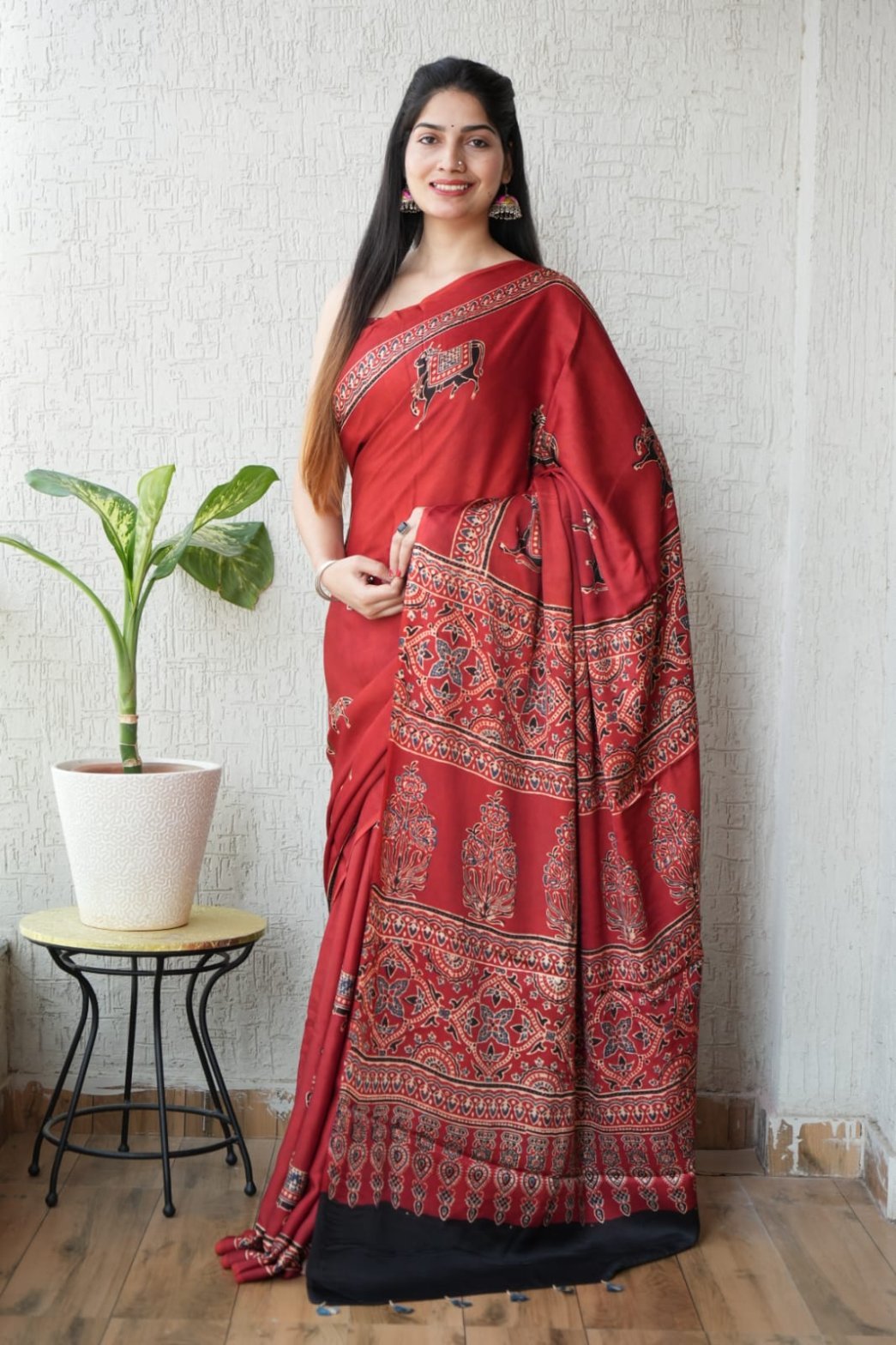 Woman wearing red Ajrakh print Modal silk saree with deer motifs and black border