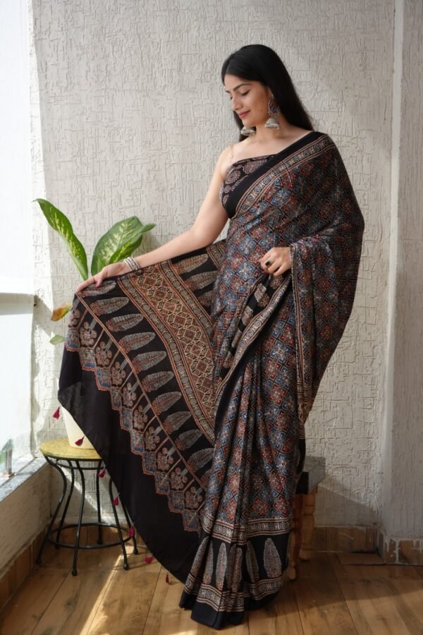 Woman draped in black Ajrakh print Modal silk saree with floral lattice and leaf border pallu