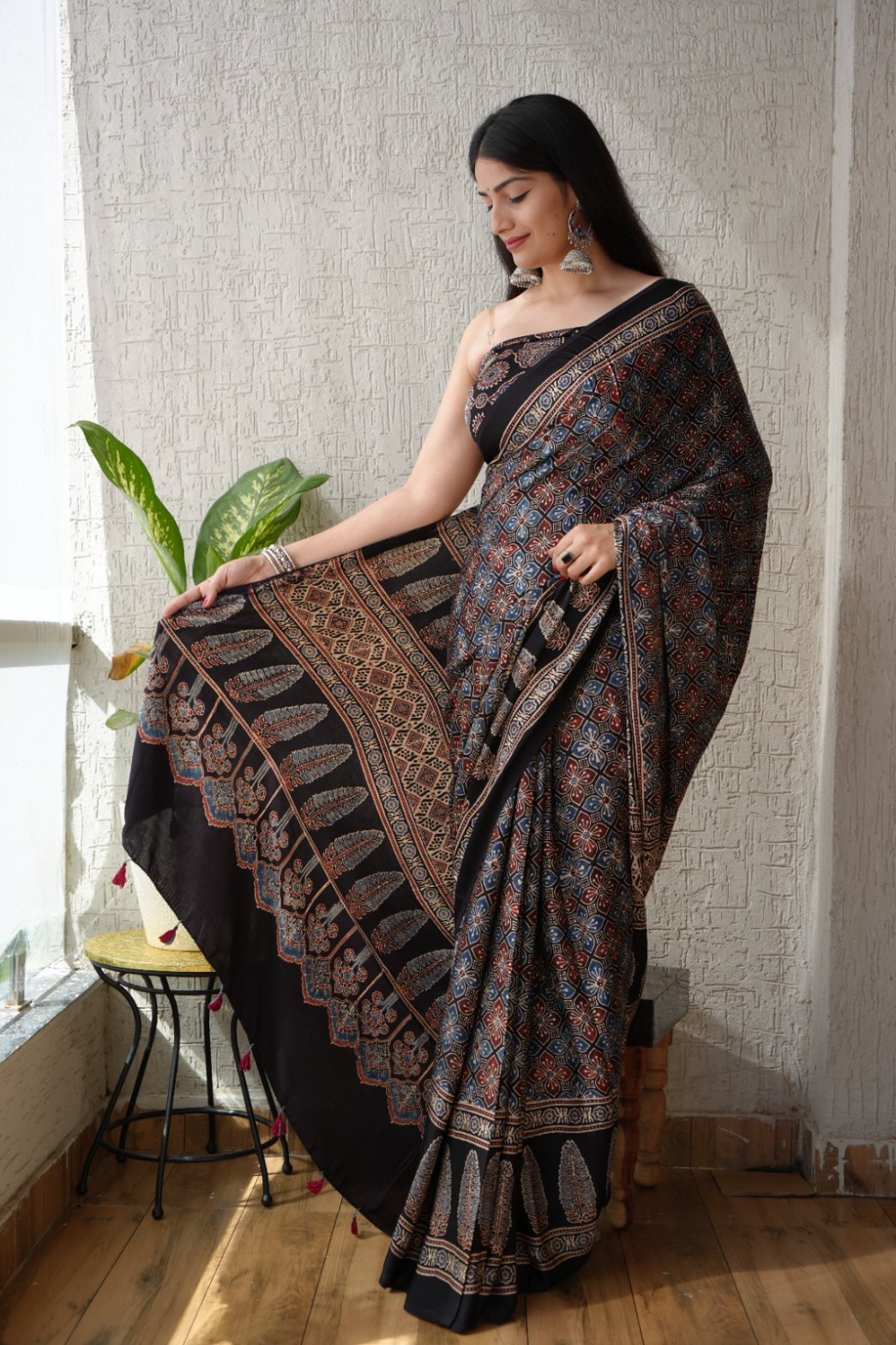 Woman draped in black Ajrakh print Modal silk saree with floral lattice and leaf border pallu