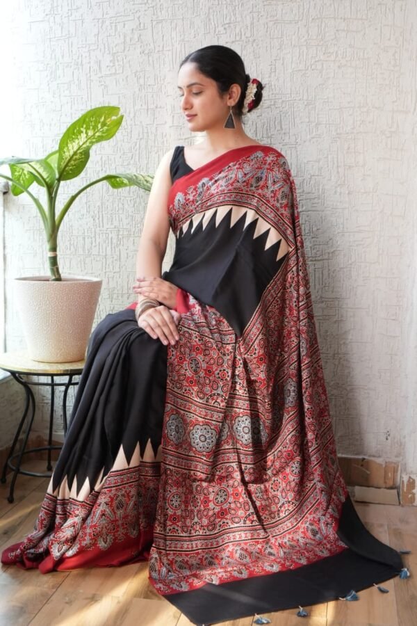 Woman draped in black Ajrakh print saree with ivory chevron border and red floral pallu
