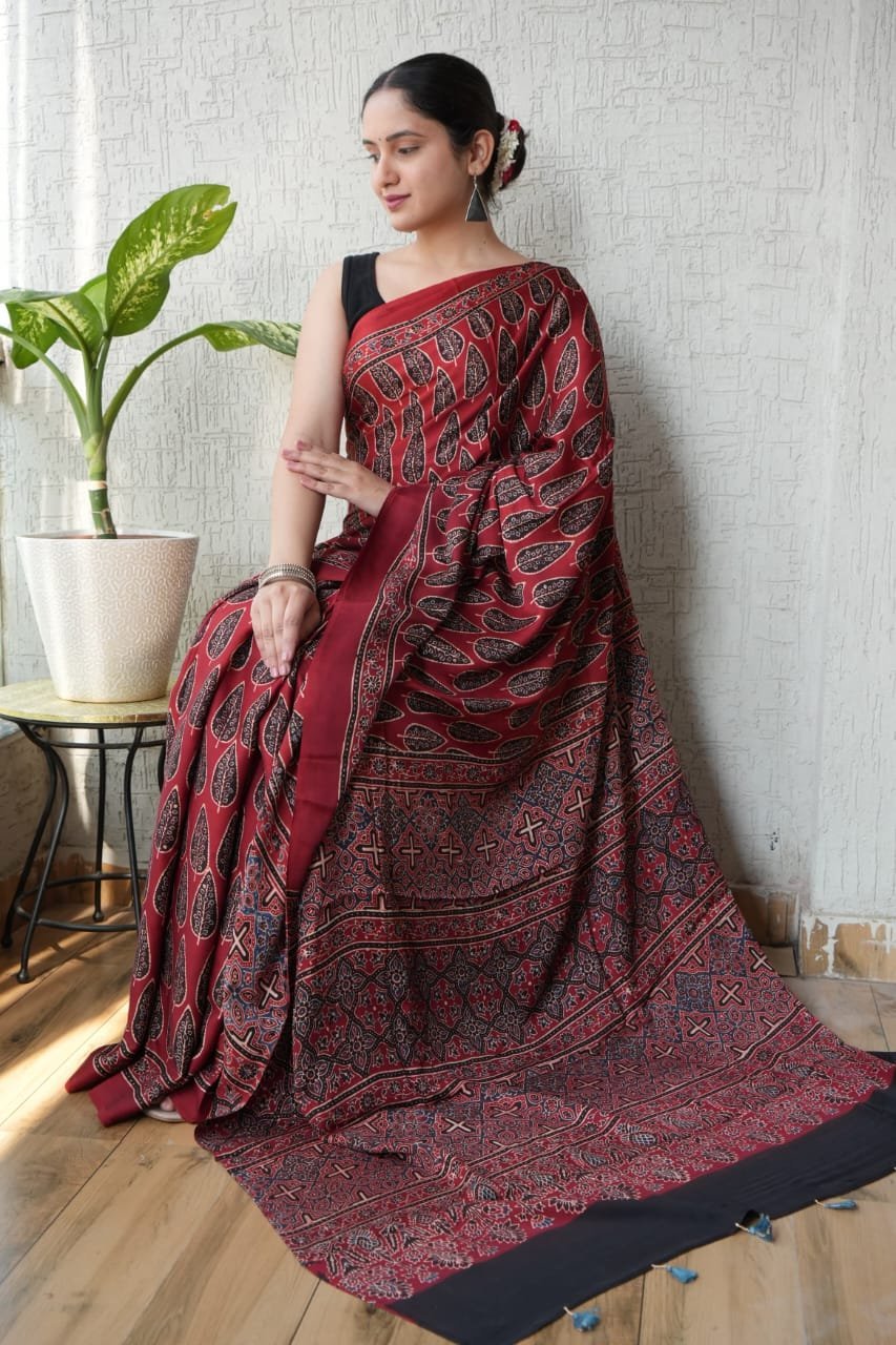 Woman draped in maroon Ajrakh print Modal silk saree with leaf motifs and geometric lattice border