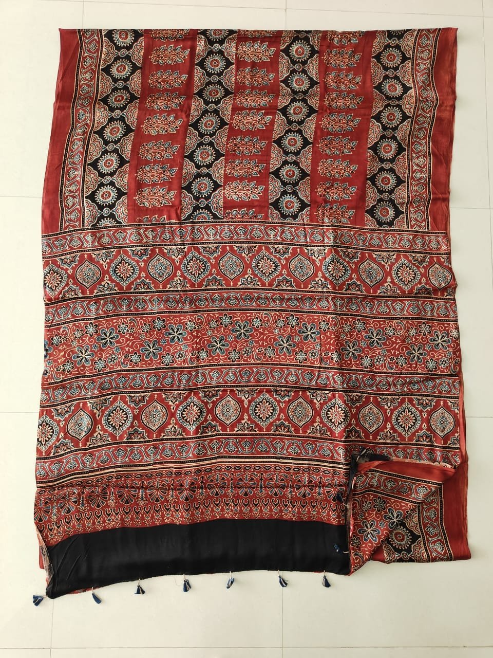 Black Ajrakh print pure Modal silk saree with rust-red floral border and navy tassels