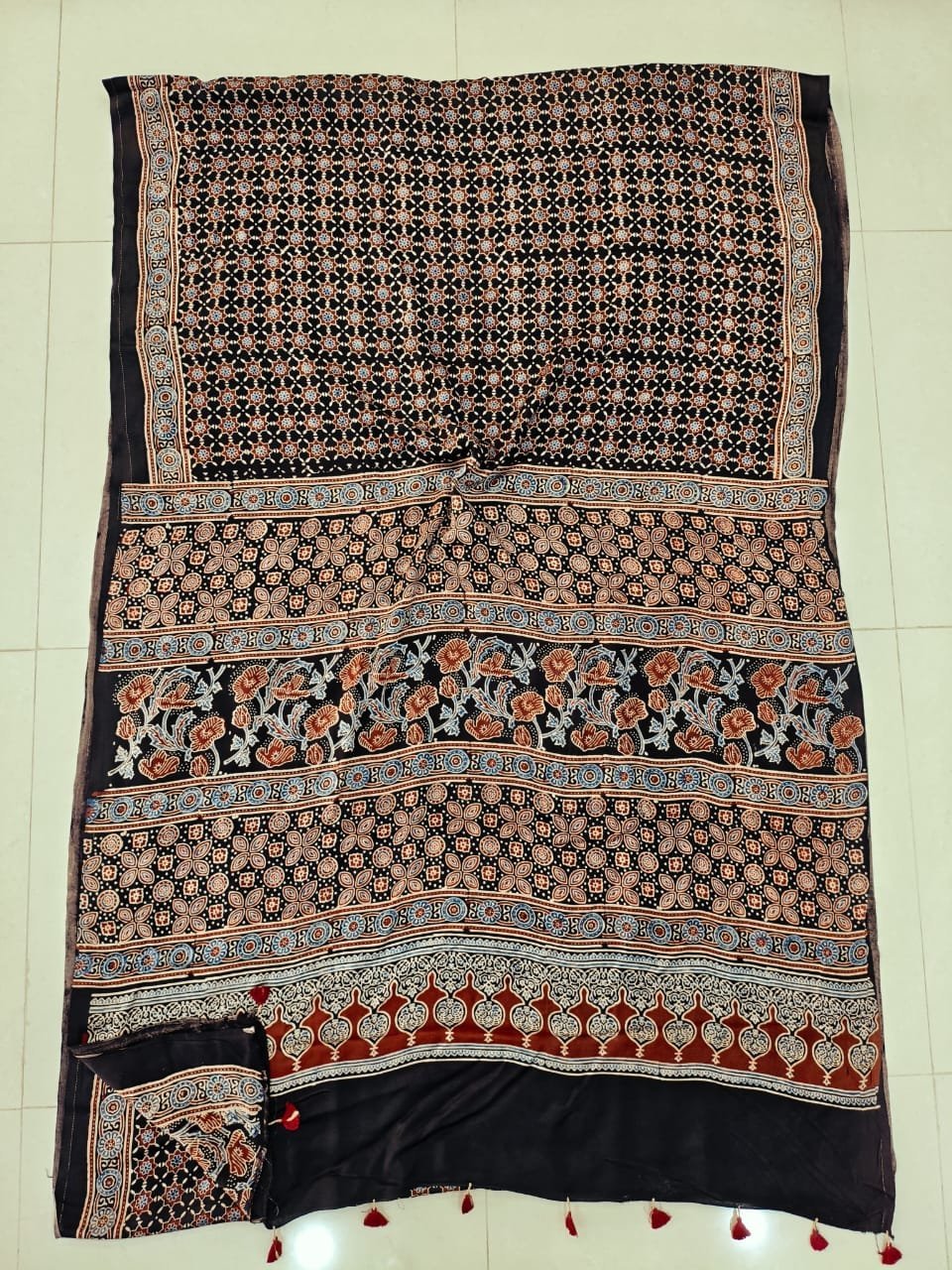 Black Ajrakh print pure Modal silk saree with rust floral vine pallu and tasseled border