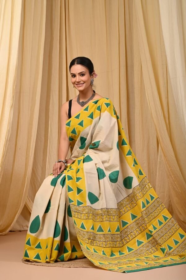 Woman in off-white Bagru print mul cotton saree with green leaf motifs and yellow geometric border