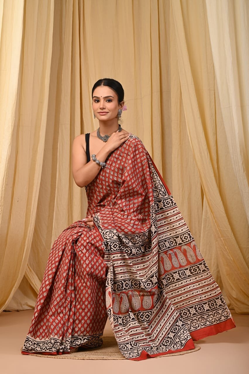 Woman draped in rust red mul cotton Bagru print saree with paisley booti and geometric border