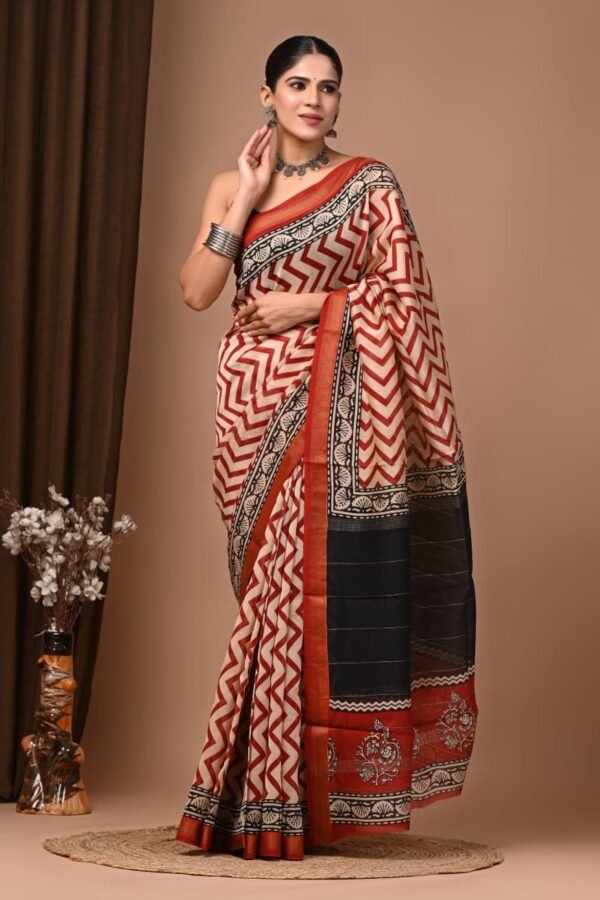 Woman wearing rust-red chevron hand block printed Maheshwari silk saree with black floral pallu