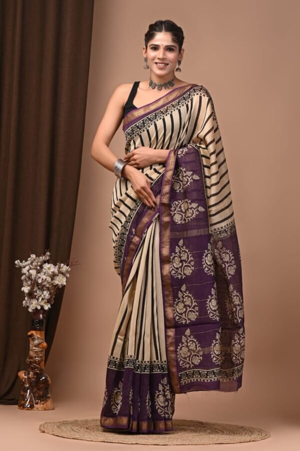 Woman wearing cream and black striped Maheshwari silk saree with purple floral block printed border