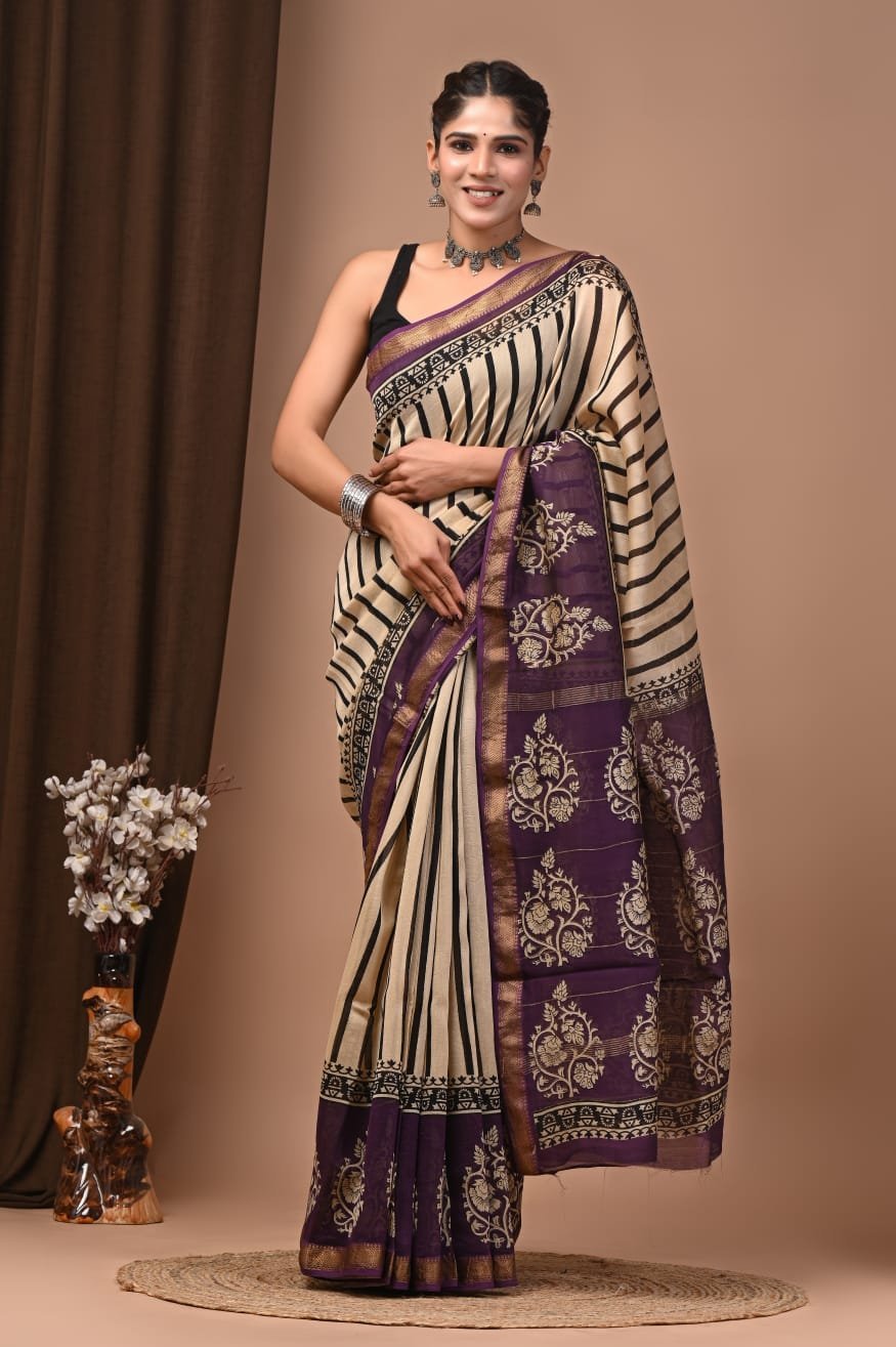 Woman wearing cream and black striped Maheshwari silk saree with purple floral block printed border