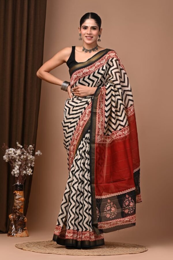 Woman wearing black and cream chevron hand block printed Maheshwari silk saree with red pallu