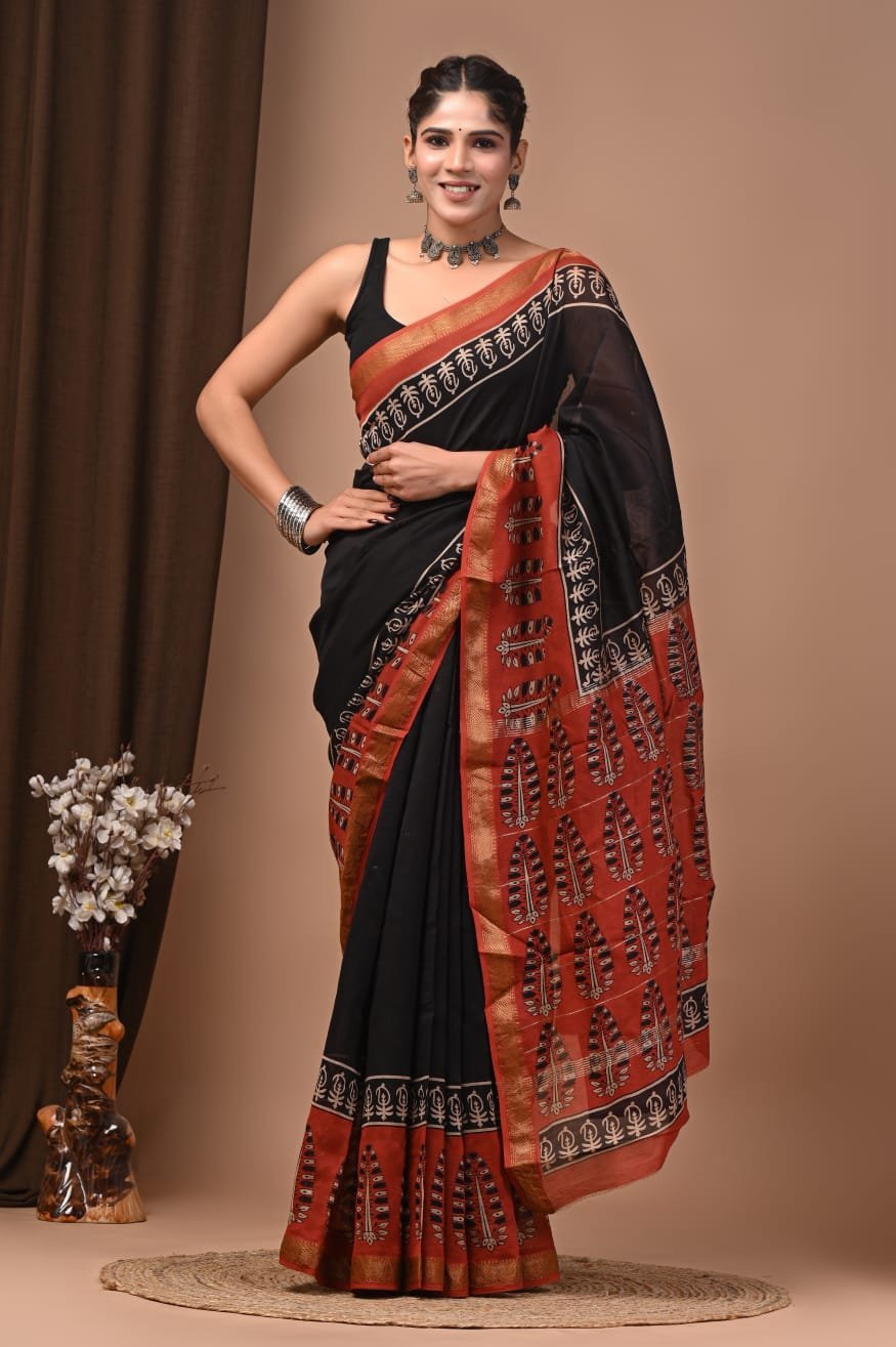 Woman wearing black hand block printed Maheshwari silk saree with rust-red leaf motif pallu
