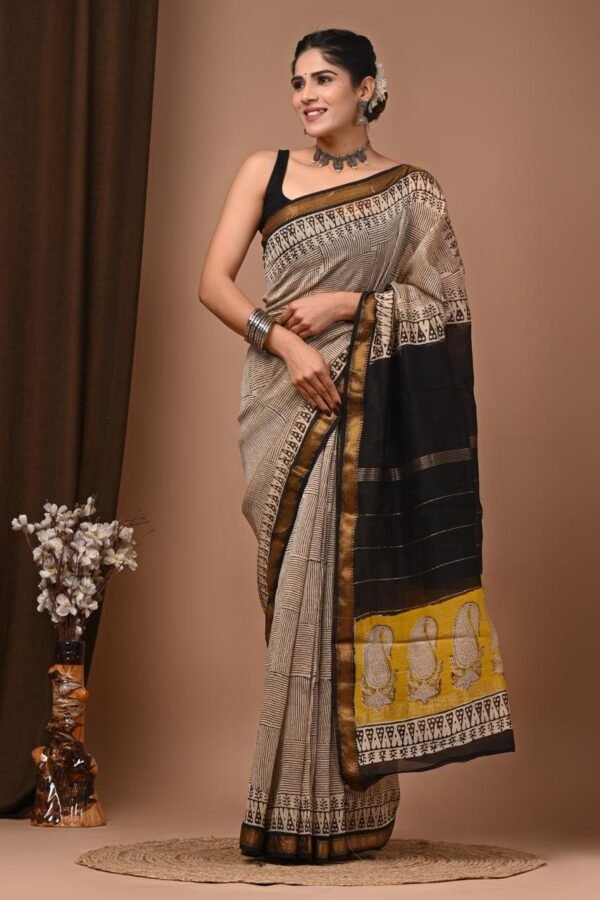 Woman wearing beige and black checked hand block printed Maheshwari silk saree with mustard paisley pallu