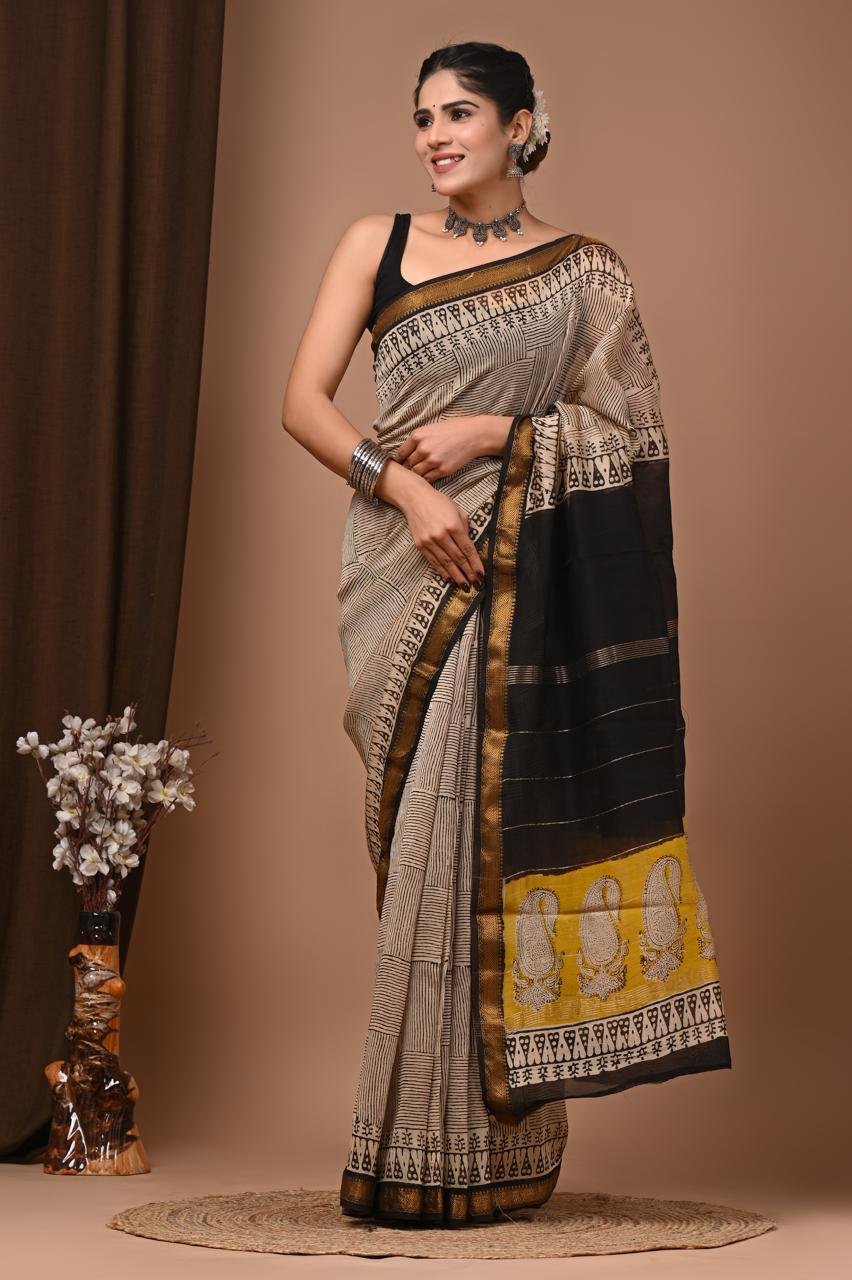 Woman wearing beige and black checked hand block printed Maheshwari silk saree with mustard paisley pallu