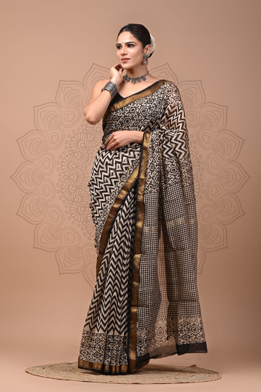 Woman draped in black and beige zigzag hand block printed Maheshwari silk saree with gold zari border
