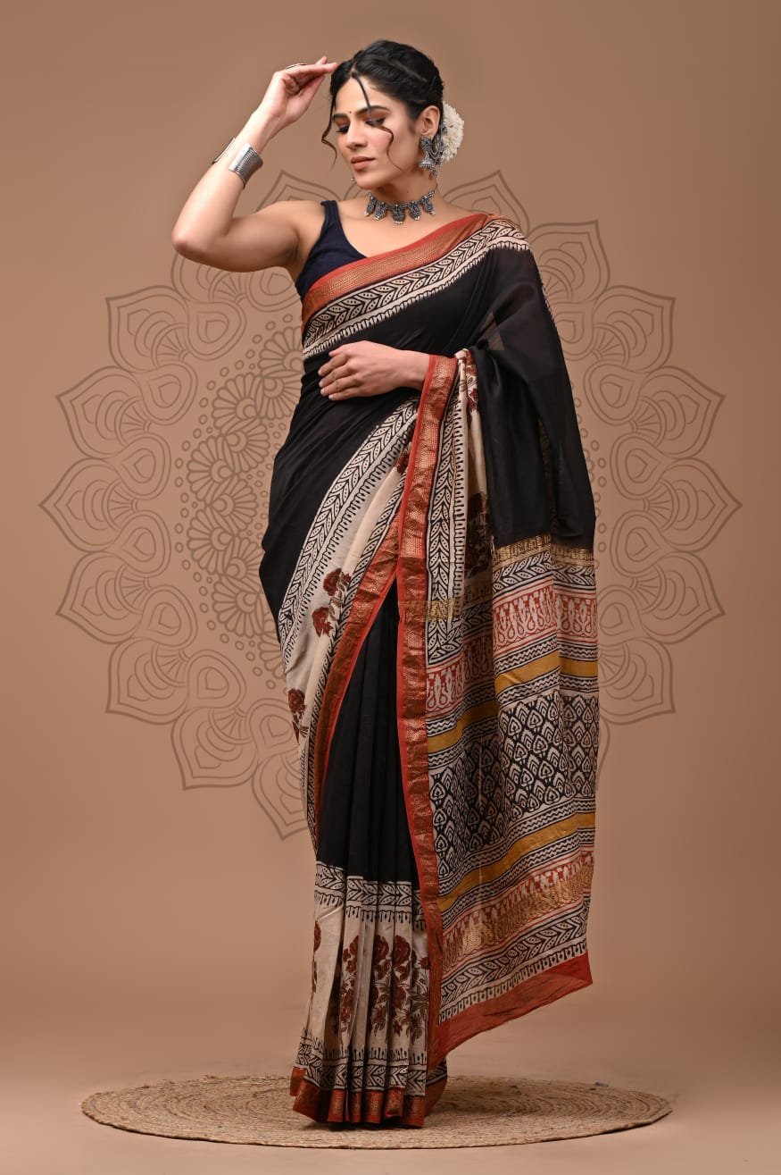 Woman wearing black hand block printed Maheshwari silk saree with floral border and geometric pallu