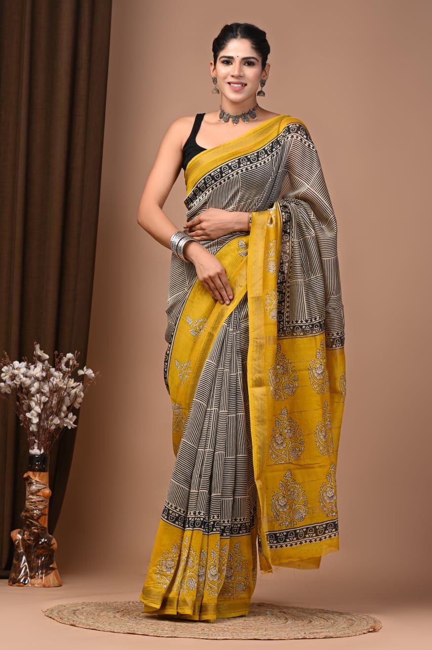 Woman wearing beige and black striped hand block printed Maheshwari silk saree with mustard floral pallu