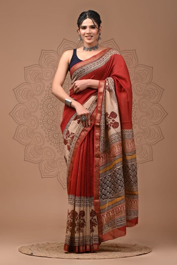Woman in rust red hand block printed Maheshwari silk saree with floral border and paisley pallu