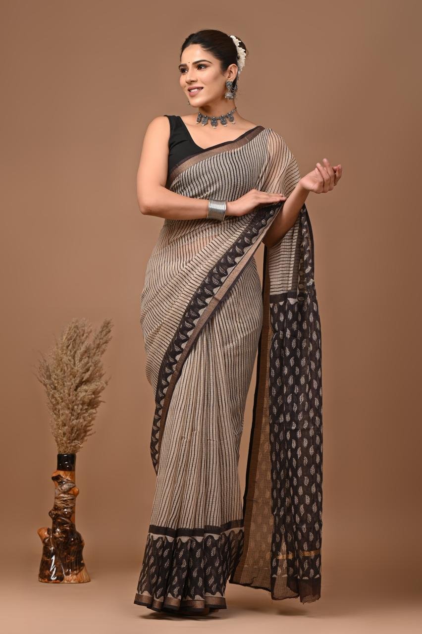Woman draped in beige Kota Doria cotton saree with black stripes and leaf booti pallu