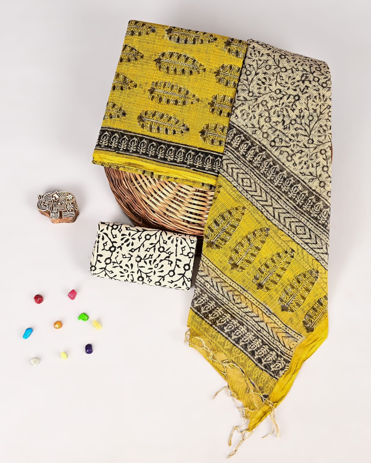 Mustard yellow Kota Doria suit with black feather motif print and zigzag border, folded with cream dupatta piece